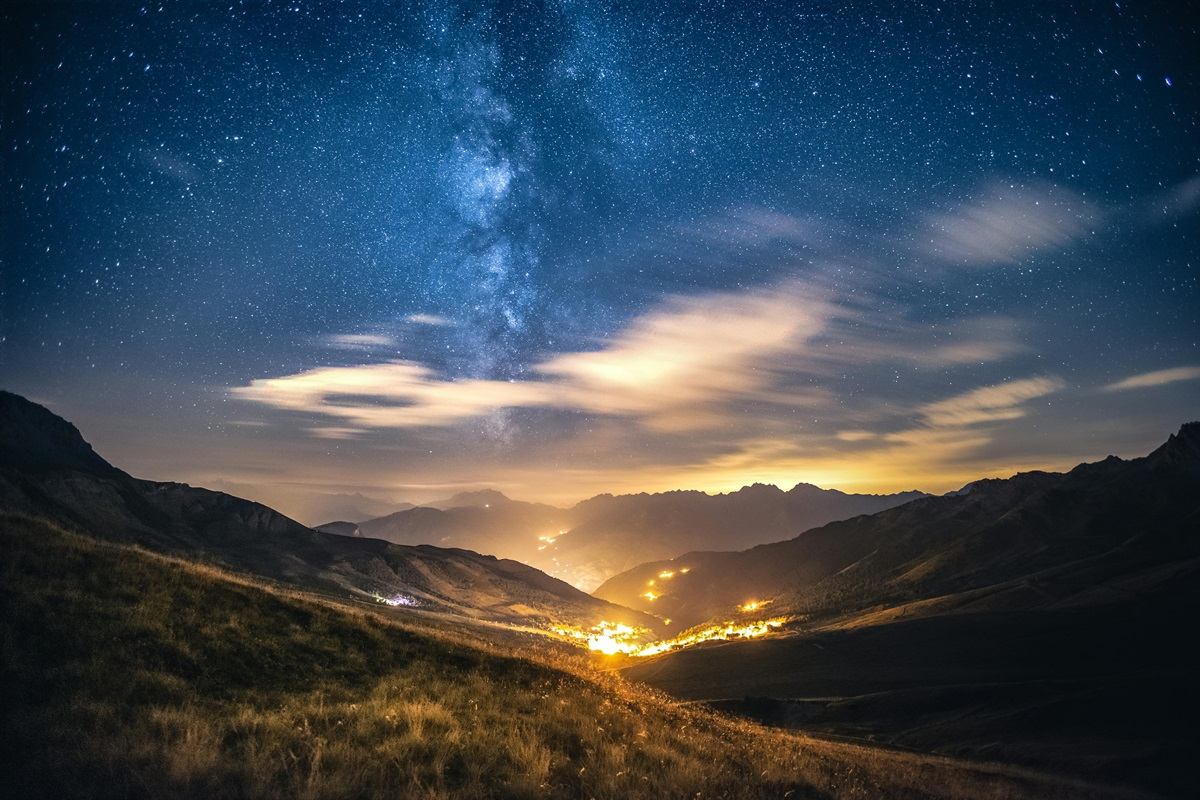 Starry night sky over a mountain valley